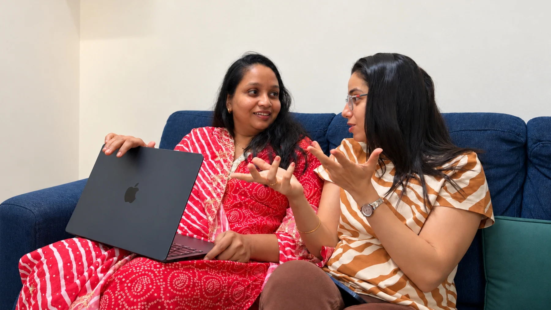Two teammates discussing a brand on a sofa with a laptop
